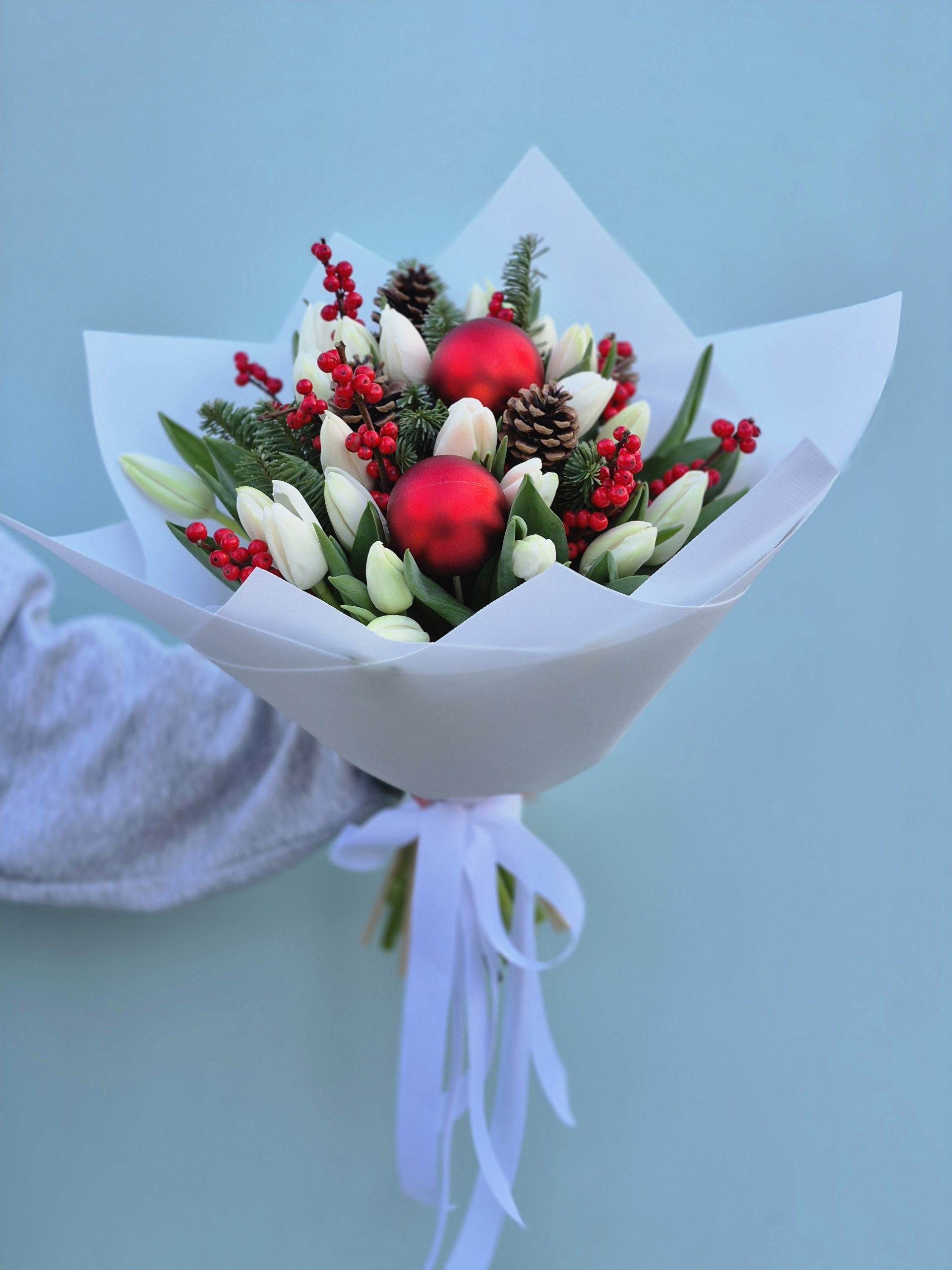 Bukiet świąteczny z białych tulipanów, szyszek, gałązek świerkowych i czerwonych ozdób.Kwiaciarnia Warszawa